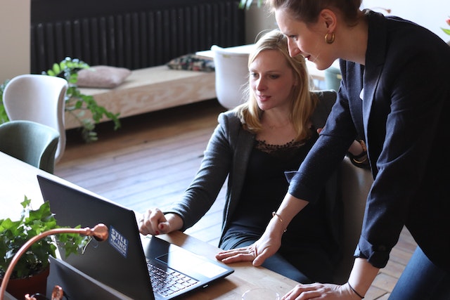 a person showing someone else something on a laptop screen